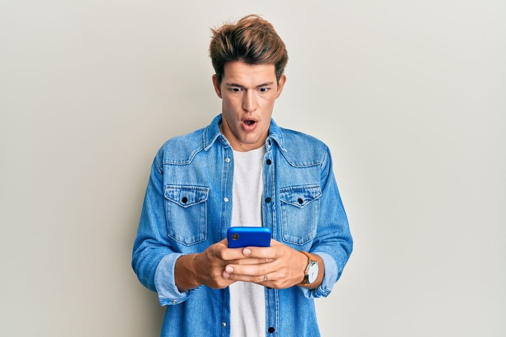 Geschrokken jonge man, die een phishing sms ontvangt over belastingschuld afkomstig van criminelen