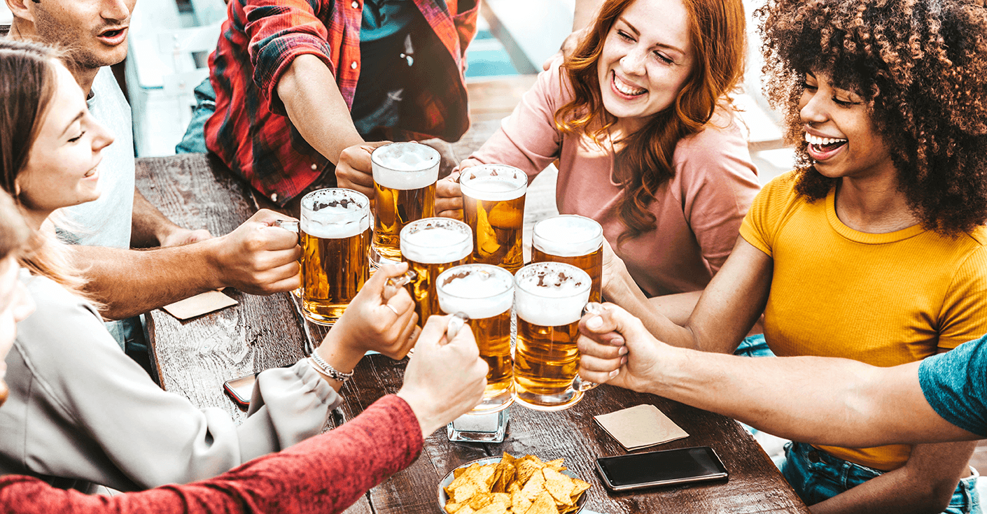 Blije mensen proostend met glas bier op terras